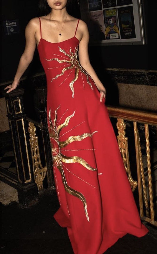 Robe de bal longue rouge en satin ornée de perles dorées, bretelles spaghetti et coupe trapèze. Inspiration pour tenue de soirée AB1377